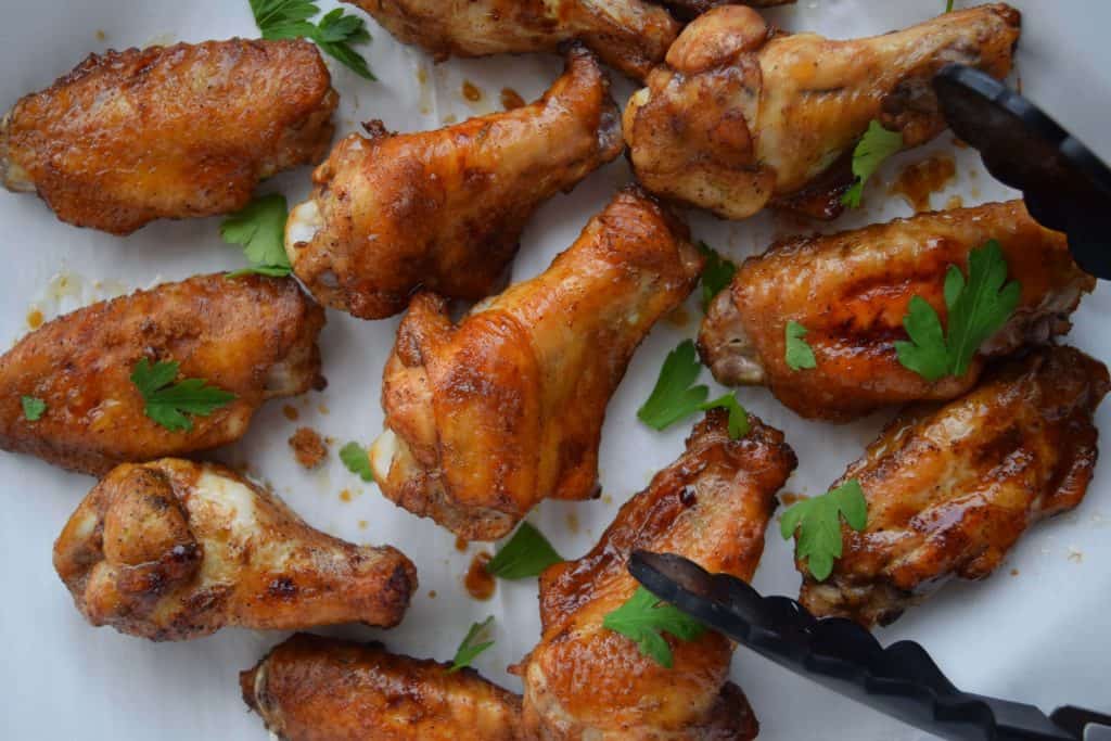 Easy Five Spice Chicken Wings on parchment with black tongs