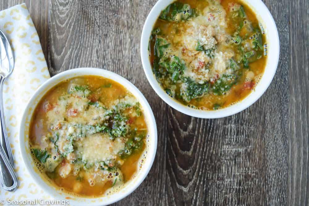 Tuscan Chickpea Soup with Kale in two white bowls with parmesan on top