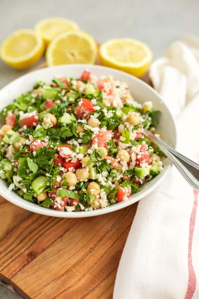 Cauliflower Tabbouleh on a white plate with lemons