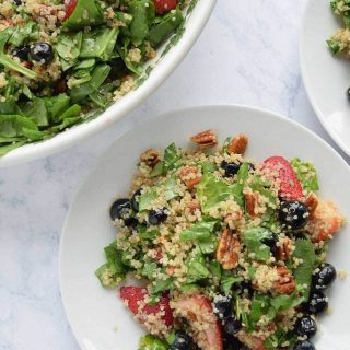 A plate of quinoa salad with spinach and berries.