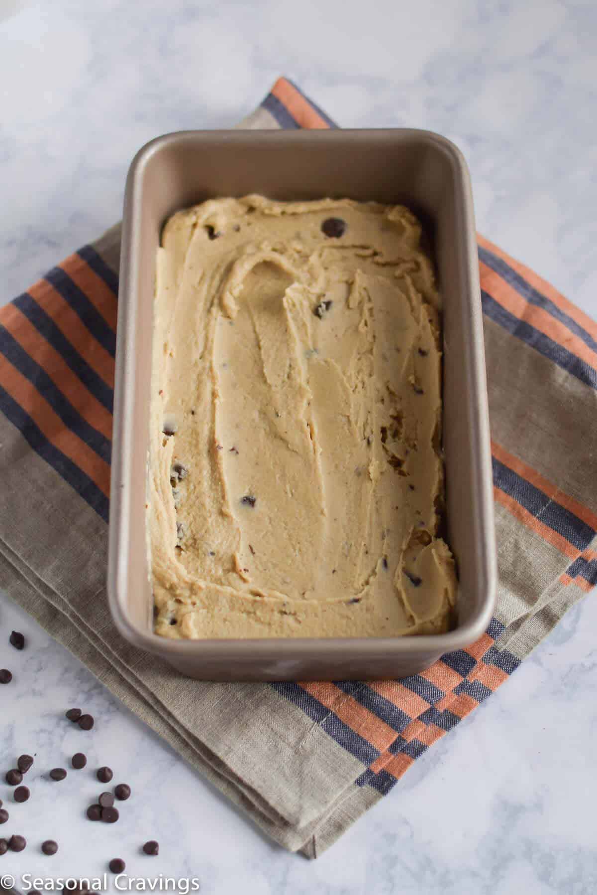 Coconut Ice Cream in a loaf pan on a striped towel