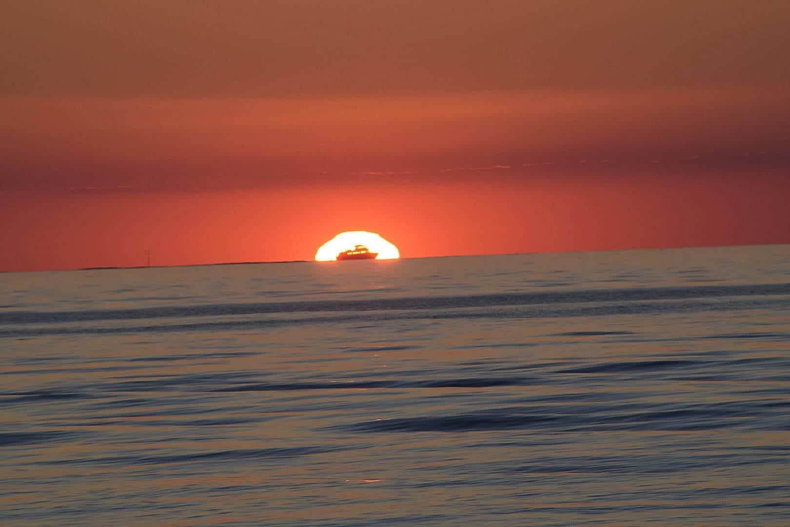 Ocean sunset with boat in front of sun