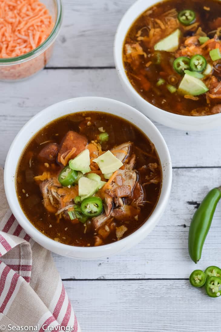 Slow Cooker Mexican Chicken Tortilla Soup with avocado, jalapenos and cheese in two small white serving bowls. #crockpot