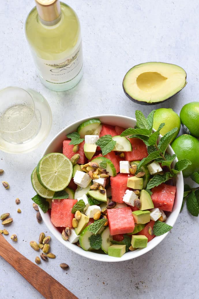 Watermelon cucumber and feta salad recipe in a white bowl with wine