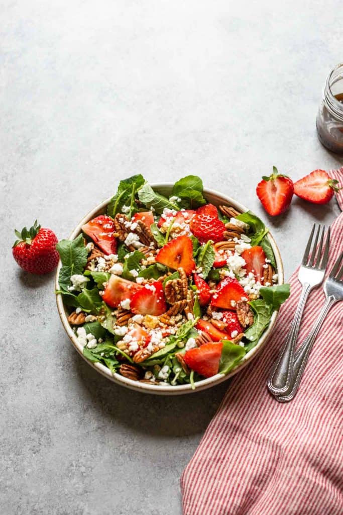 overhead shot of strawberry feta salad with sliced strawberries, pecans and feta cheese