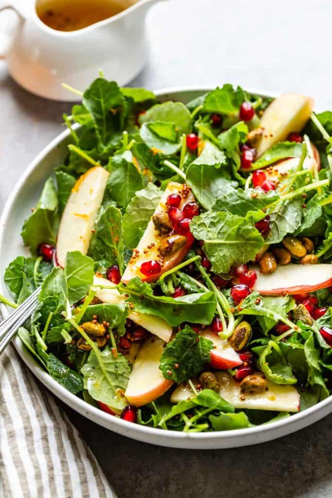 close up off kale salad with apples and pomegranate arils