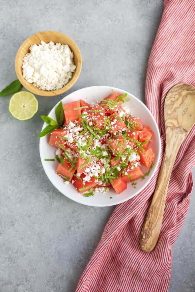 skinny watermelon feta salad in white bowl with wooden spoon