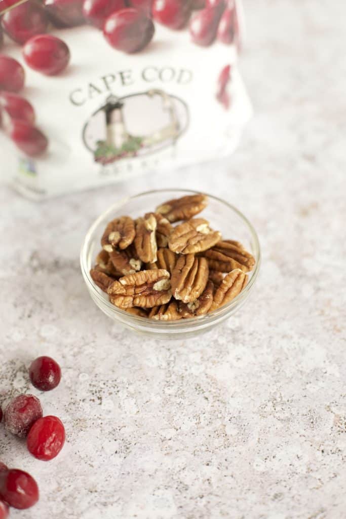 pecans in a bowl with frozen cranberries on the side