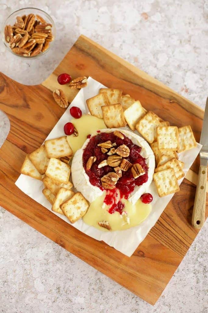 baked brie with cranberry sauce and pecans on a cutting board