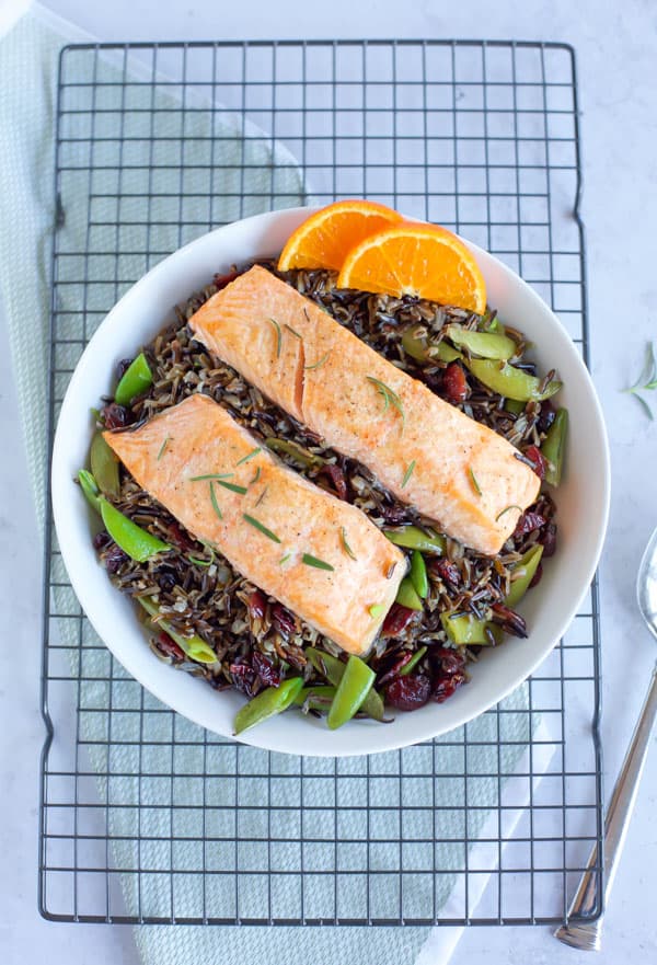 baked salmon with black rice in a big white bowl on a cooling rack