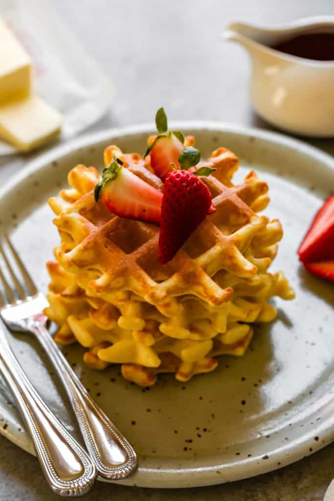 gluten free waffles on a blue plate stacked up with strawberries