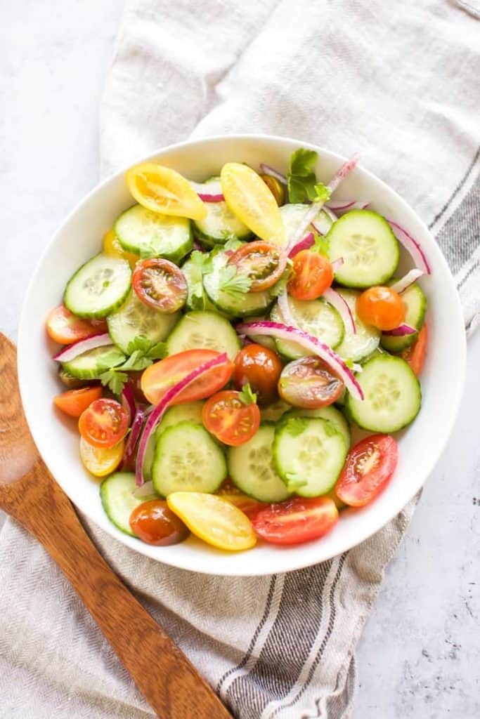 cucumber tomato salad in a white bowl