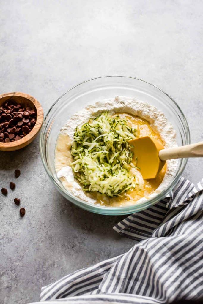 gluten free zucchini bread with batter in a large bowl with shredded zucchini