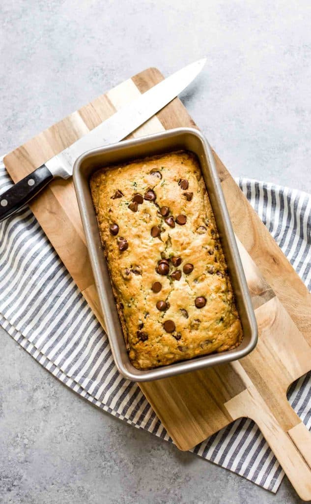 baked zucchini bread in a loaf pan with a knife