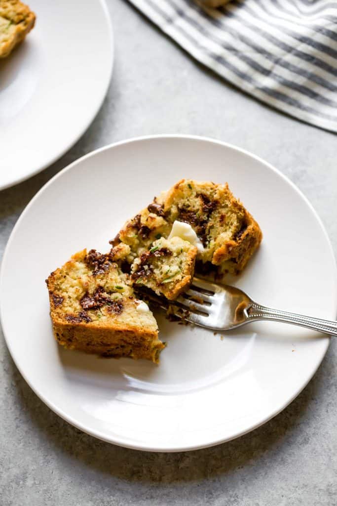 slice of zucchini bread on a white plate with butter