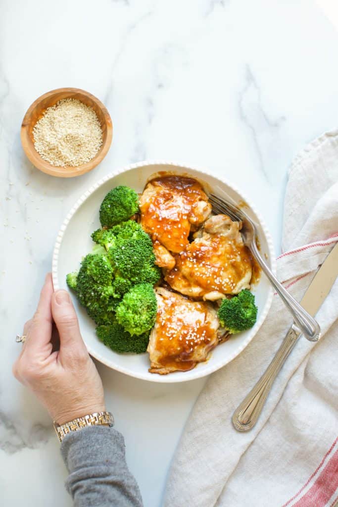 instant pot chicken teriyaki with sesame seeds with hands on the bowl