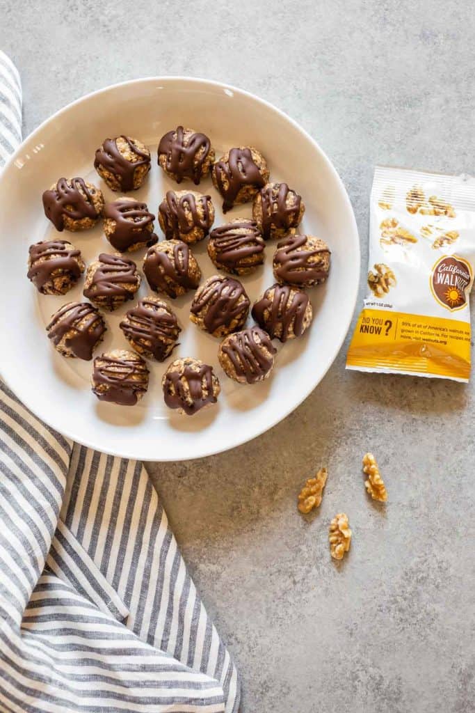 bliss balls in a white bowl with walnuts