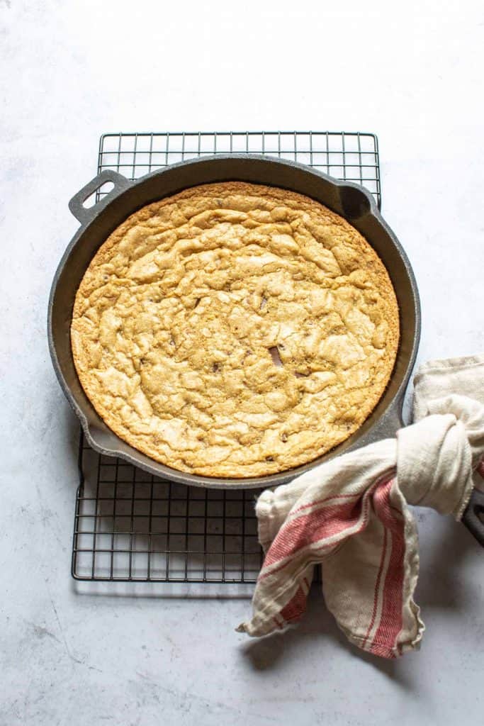 chocolate chip skillet cookie in a cast iron pan on a cooling rack