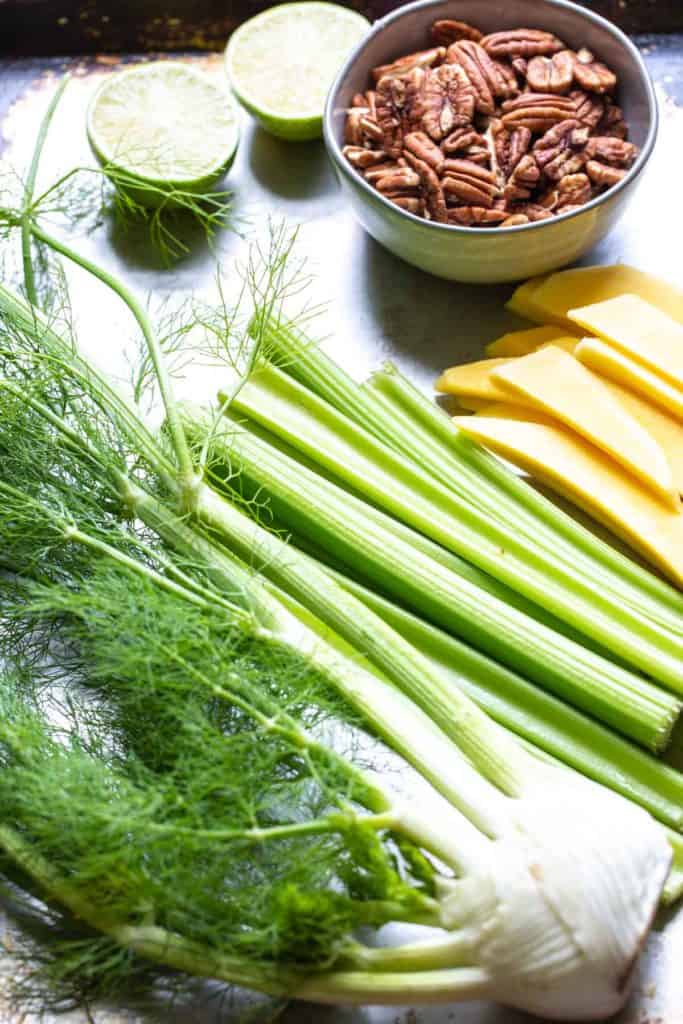 limes, pecans, fennel, mango and celery on a sheet pan