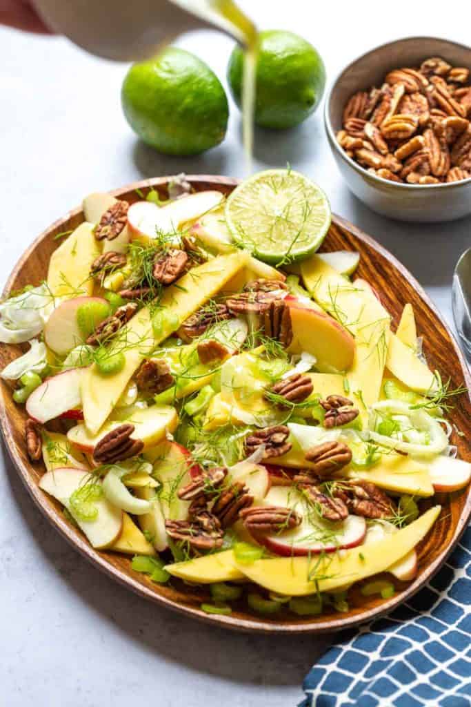 dressing being poured from above onto the fennel salad with pecans