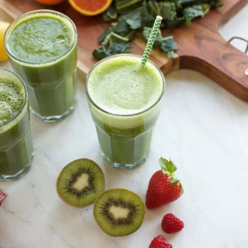 3 green smoothies in glasses with fruit on the side