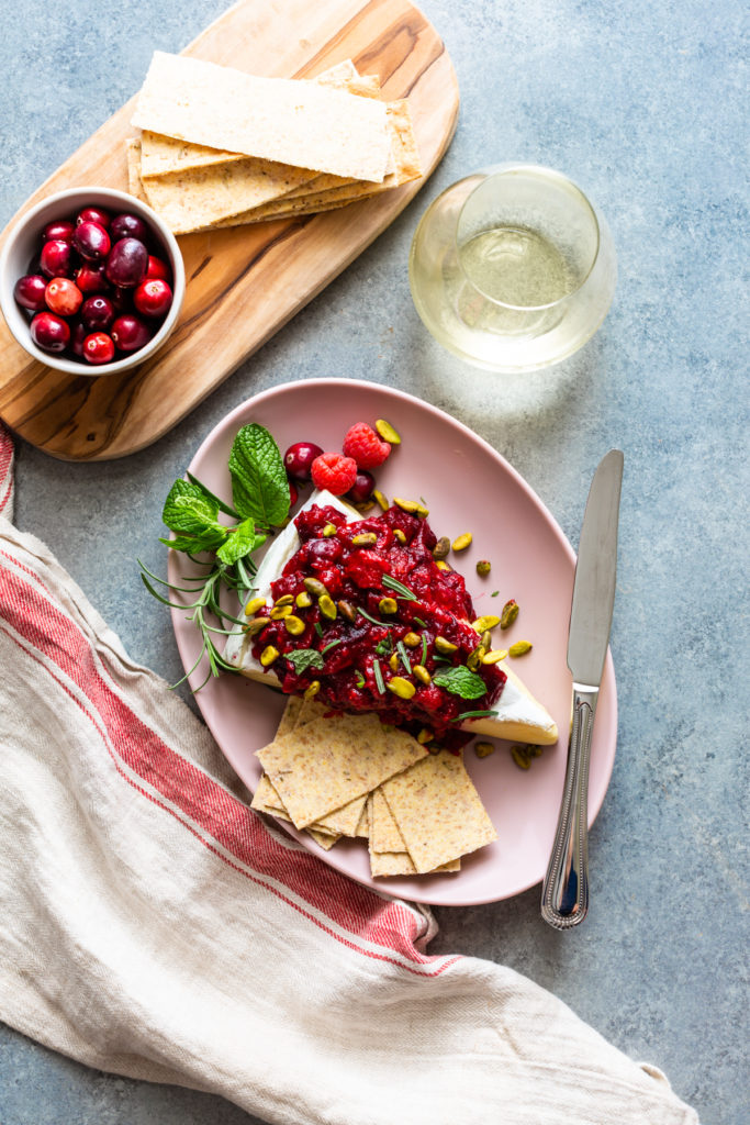 Baked brie with cranberry sauce on a pink plate with wine