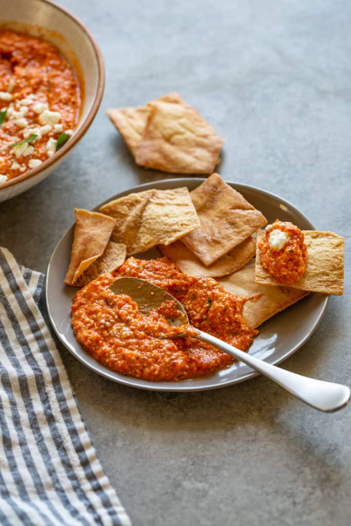 roasted red pepper dip with pita chips and a spoon