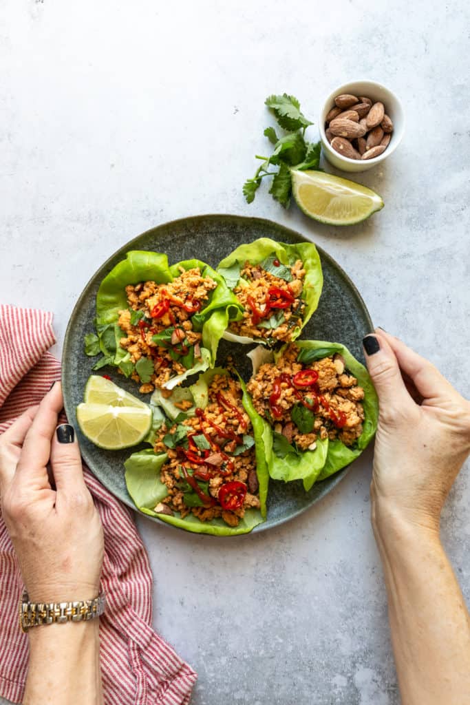 thai lettuce wraps recipe on plate with hands on sides