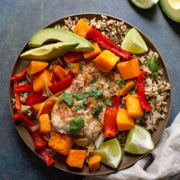 A sheet pan baked cod with butternut squash on a blue background.