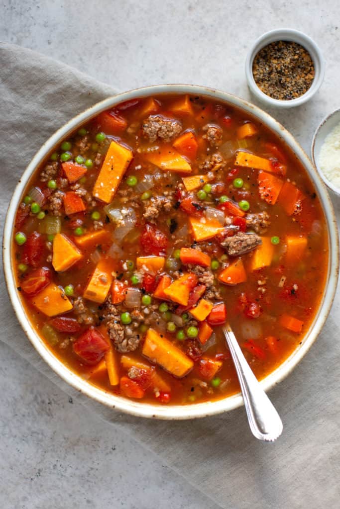 hamburger soup with vegetables in a bowl with a spoon