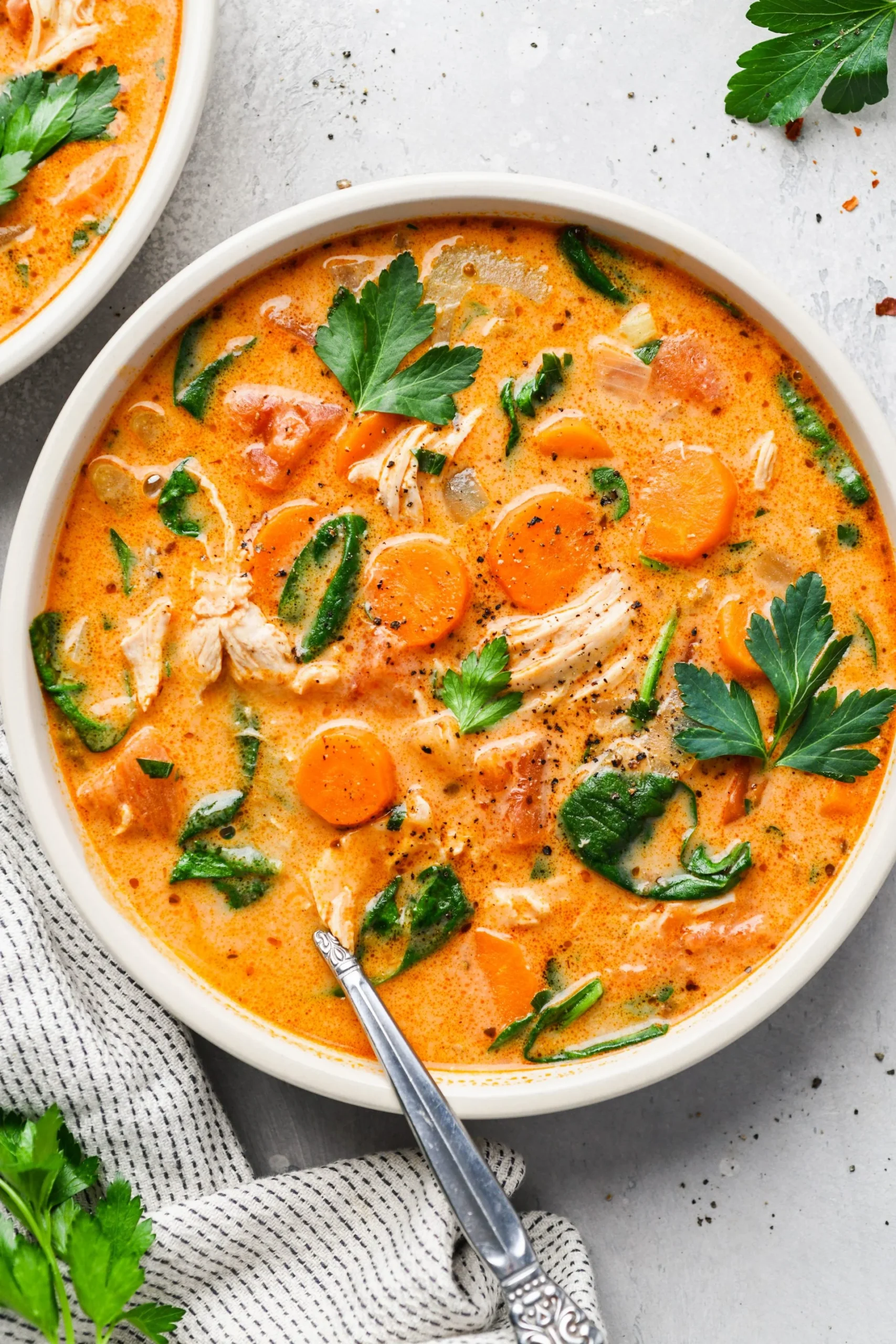 A gluten-free bowl of chicken soup with carrots and parsley.