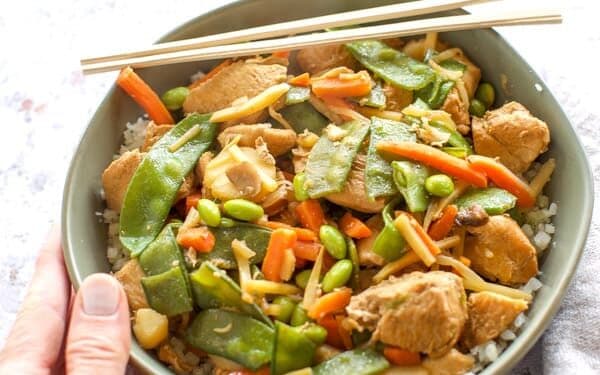 chicken stir fry in a green bowl with chopsticks