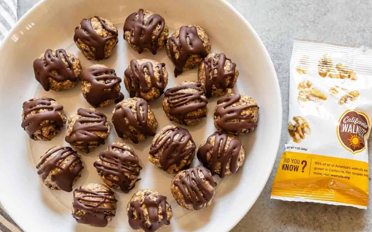 banana bliss balls in a white plate with walnuts on the side