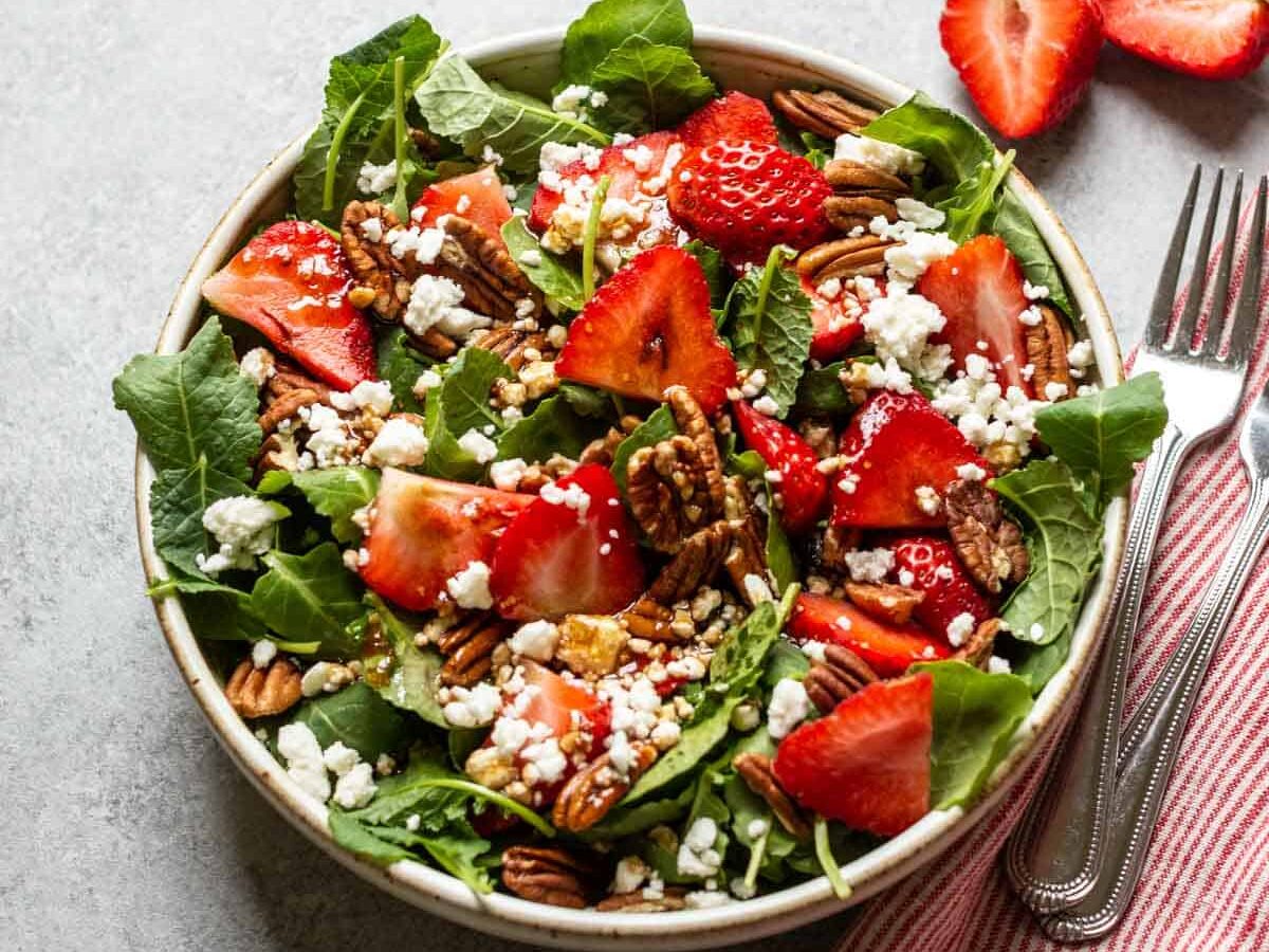 strawberry and pecan salad with feta cheese in a white bowl