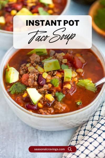 A bowl of Instant Pot taco soup garnished with avocado, cilantro, corn, and ground meat is displayed beside a spoon and a cloth napkin. Text overlay reads "Instant Pot Taco Soup".