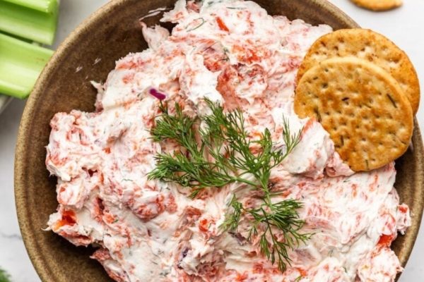 A bowl of crawfish dip with crackers and celery.