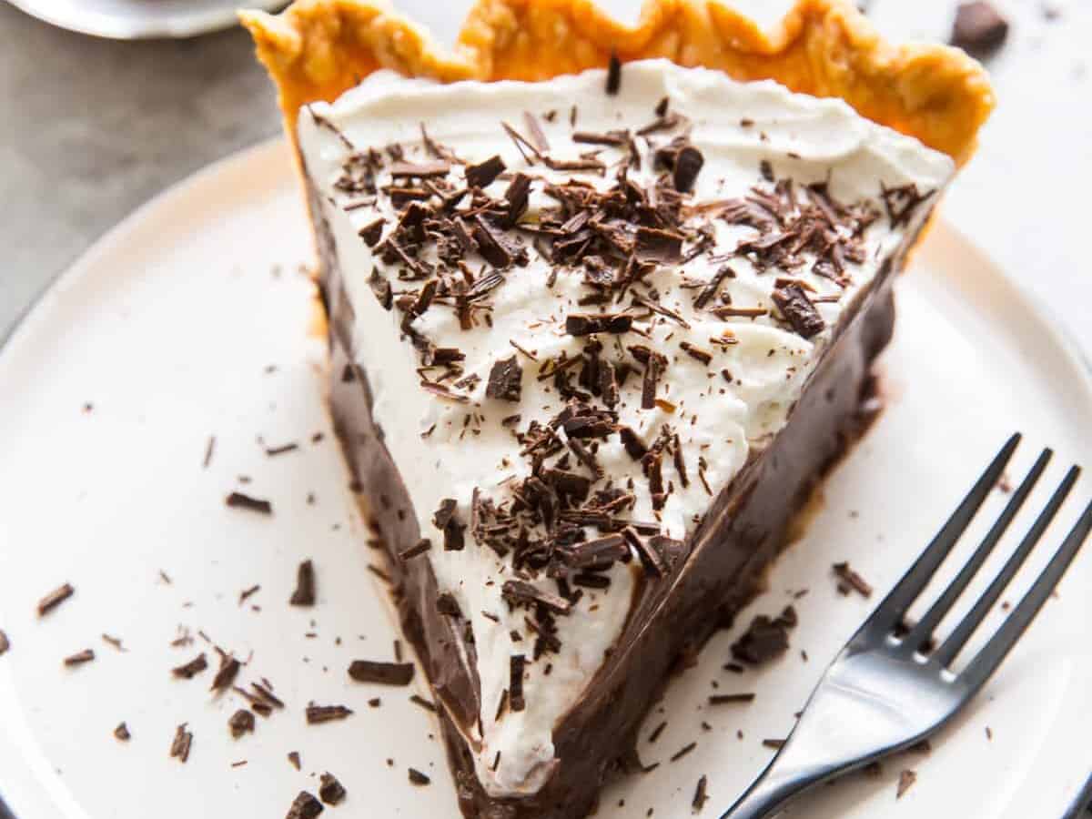 A slice of chocolate cream pie with chocolate shavings and a spoon.