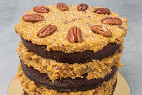 Three layers of chocolate cake with pecans on top.