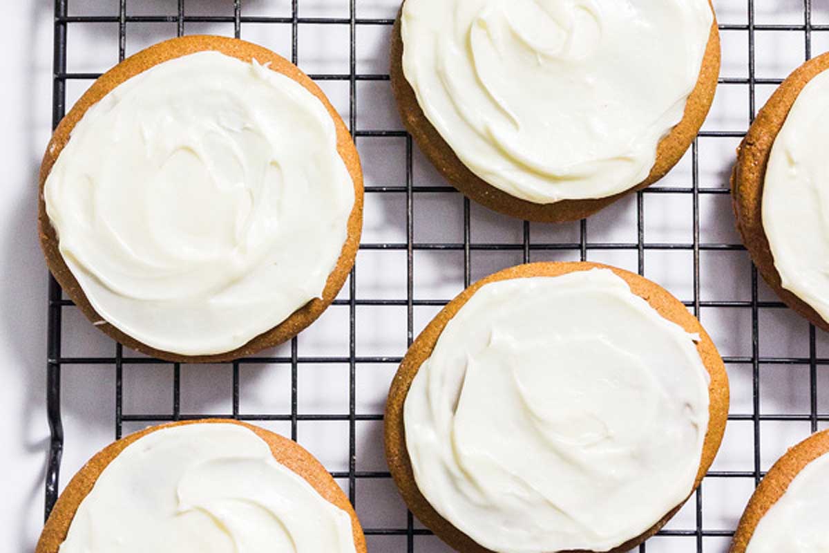 Ginger cookies with icing on a cooling rack.