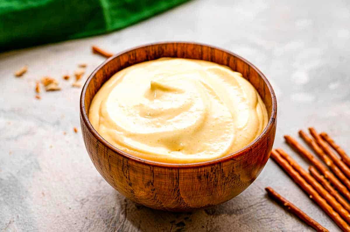 Whipped cream in a wooden bowl with cinnamon sticks.