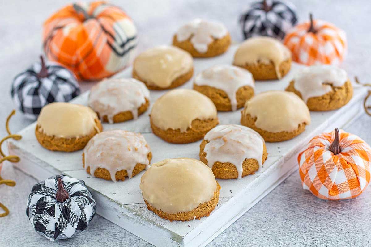 Pumpkin cookies with icing on a white plate.