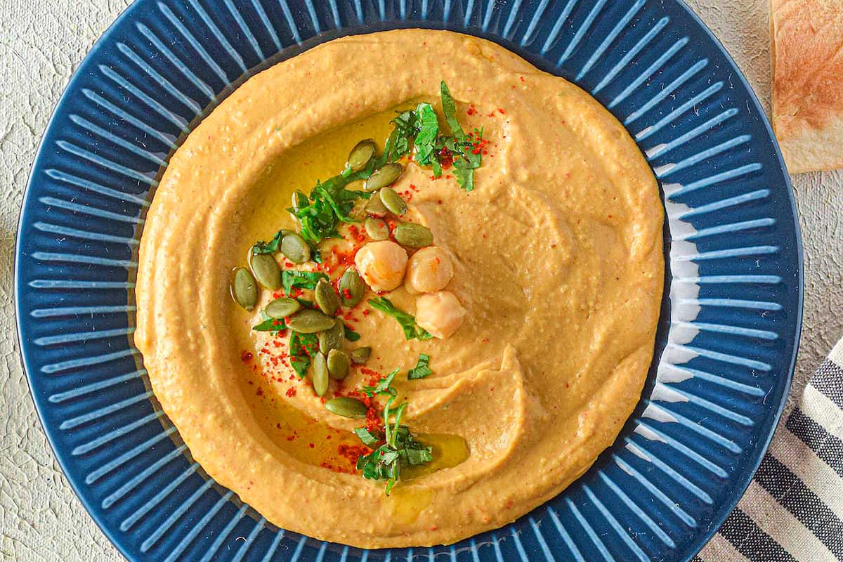 Hummus on a blue plate with bread on the side.