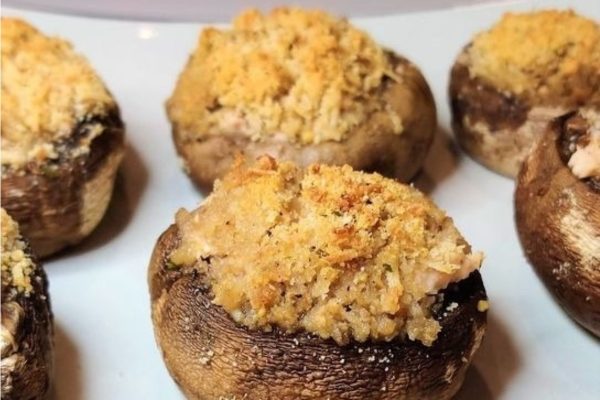 Four stuffed mushrooms on a white plate.