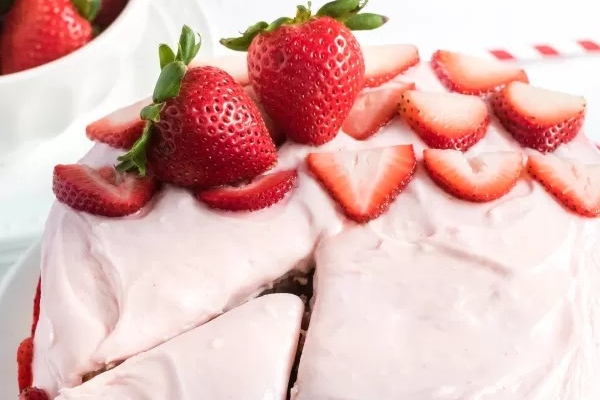 A slice of strawberry cake on a white plate.