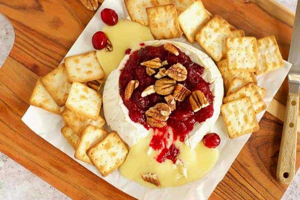 A cheese platter with crackers and cranberry sauce.