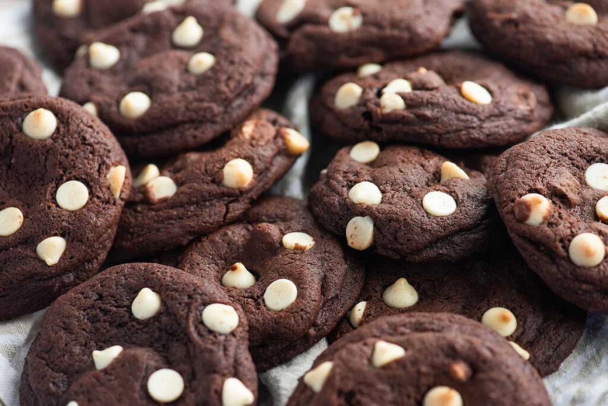 A pile of chocolate cookies with white chocolate chips.