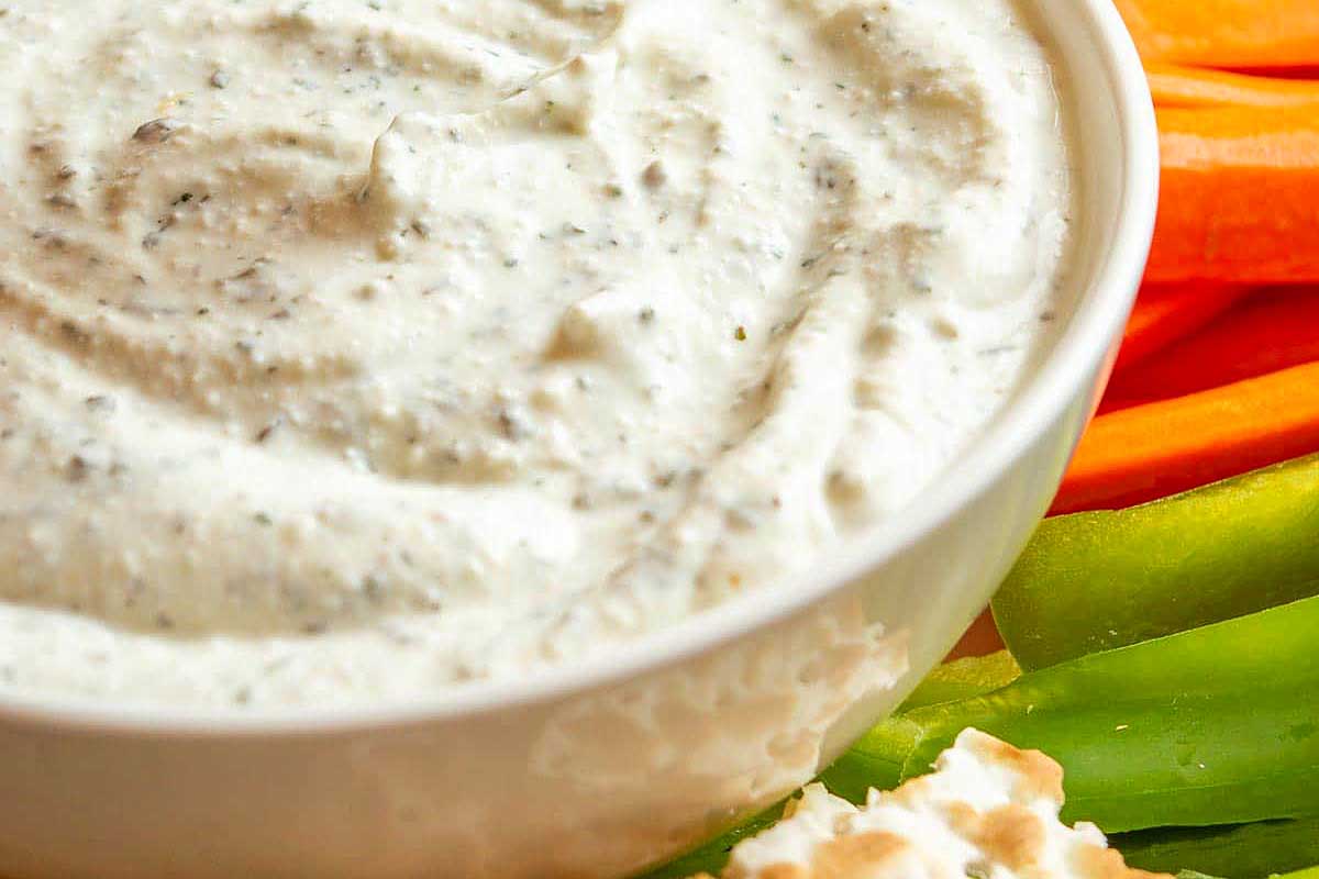 A bowl of dip with carrots and celery.