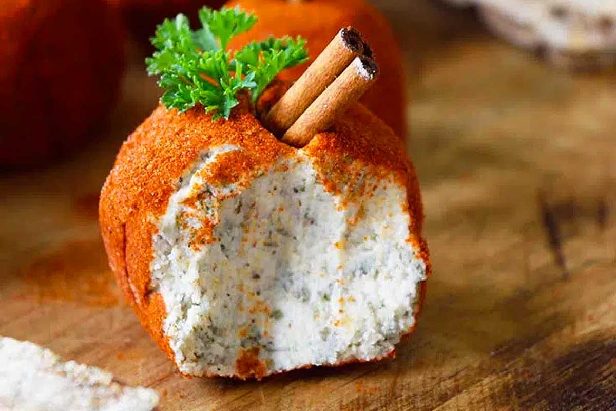 Pumpkin cheese balls on a wooden cutting board.