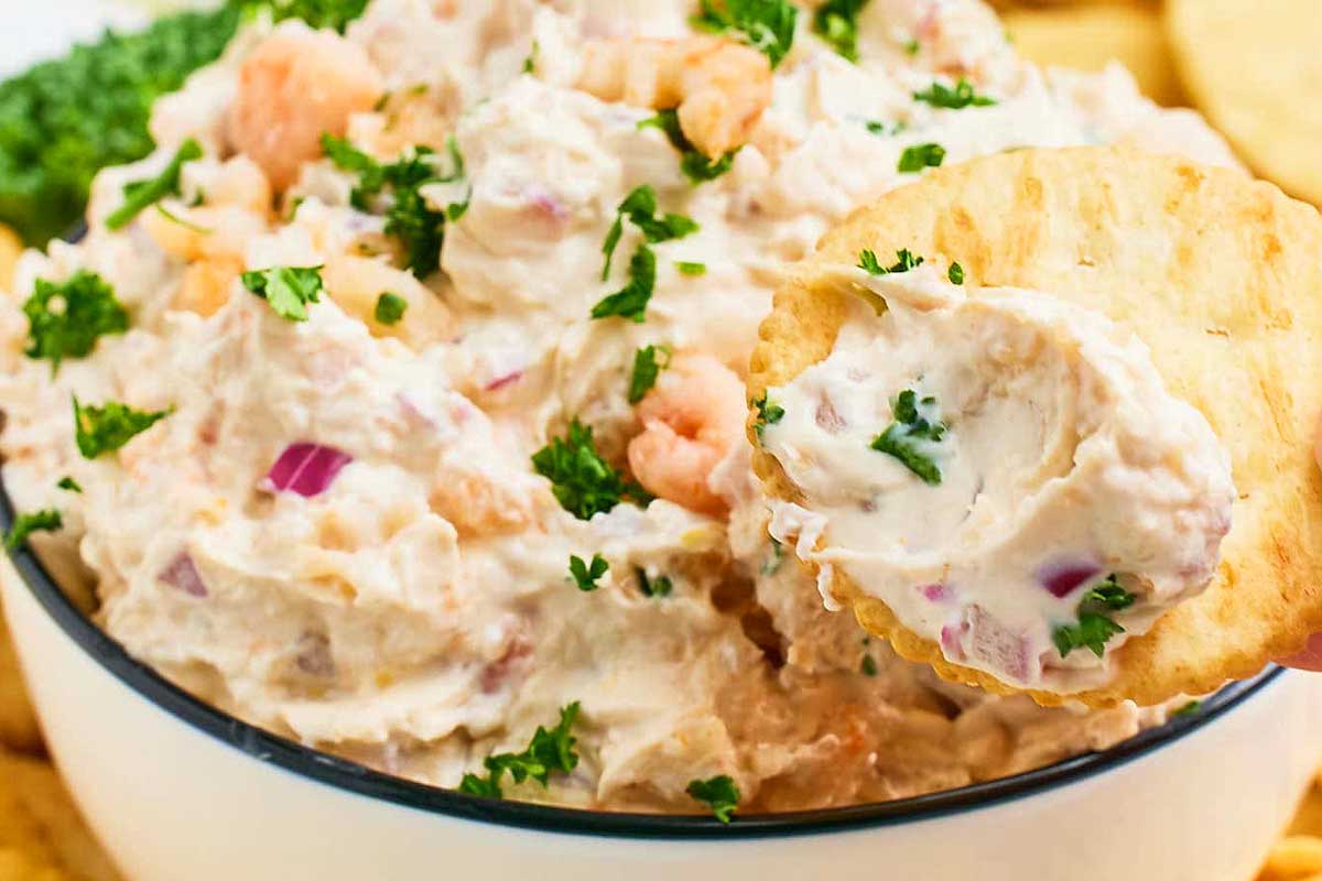 A person is holding a bowl of shrimp dip.