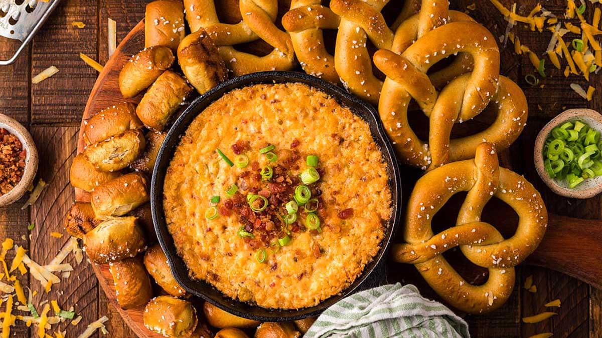 A bowl of dip with pretzels and pretzel sticks.